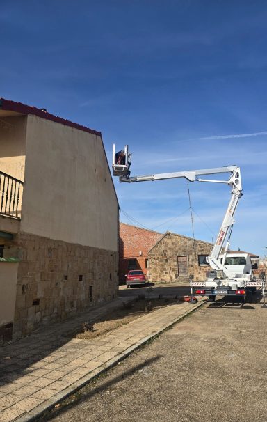 Trabajadores en una grúa elevadora reparando la fachada de un edificio.
